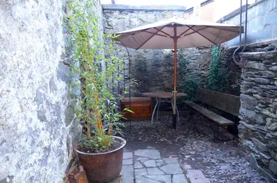 a patio with an umbrella and a table and a bench at Cynfaen house in Corwen