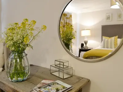 a vase of flowers on a table with a mirror at Maes Y Bryn Farmhouse in Llanwrda