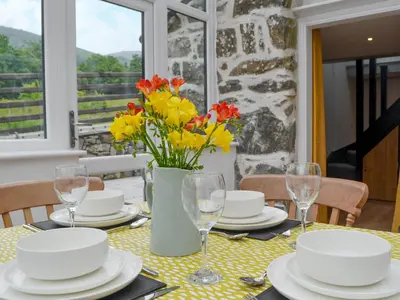 a dining table with a vase of flowers on it at Ysgoldy Salem in Mallwyd