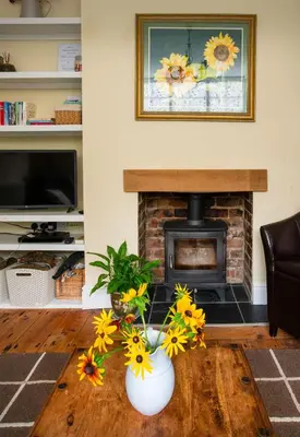 a living room with a fireplace and flowers on a table at Magnolia Cottage in Church Stretton
