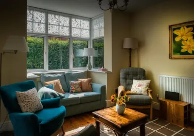 a living room with a couch and two chairs and a table at Magnolia Cottage in Church Stretton