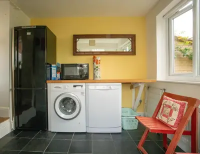 a kitchen with a washing machine and a microwave at Magnolia Cottage in Church Stretton