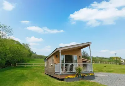 a small cabin with a balcony on a grass field at 1 Bed in Lower Chapel oc-waa906 in Lower Chapel