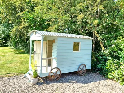 a blue shed with two large wheels in a yard at River Cottage@Cwm Mill - Riverside Family Holidays in the Black Mountains in Hereford
