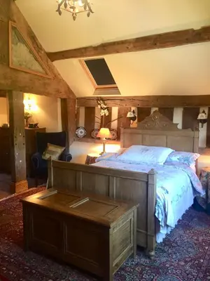 a bedroom with a large bed with a wooden headboard at Lower House Farm B&B, Herefordshire in Hergest
