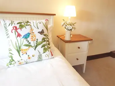 a bed with a pillow and a table with a lamp at Old Bake House Cottage @ Cwm Mill in Michaelchurch Escley
