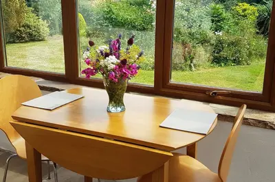 a vase of flowers sitting on a wooden table at Old Bake House Cottage @ Cwm Mill in Michaelchurch Escley