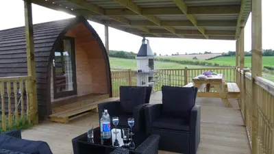 a deck with two chairs and a gazebo at Woodbatch Camping & Glamping in Bishops Castle