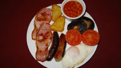 a plate of breakfast food with eggs bacon tomatoes and beans at Woodbatch Camping & Glamping in Bishops Castle