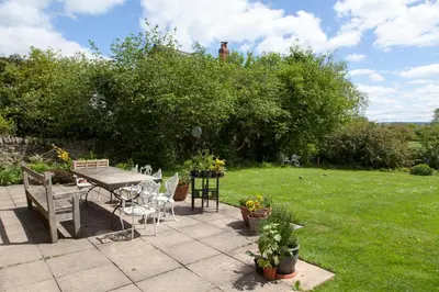 a patio with a table and chairs in a yard at Lower Buckton Country House in Leintwardine