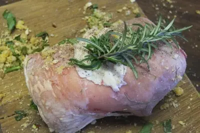 a piece of meat with rosemary on top on a cutting board at Lower Buckton Country House in Leintwardine