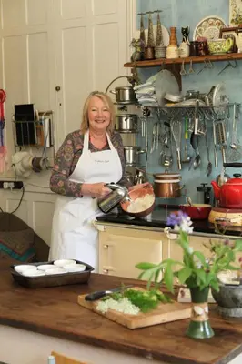 a woman standing in a kitchen preparing food at Lower Buckton Country House in Leintwardine