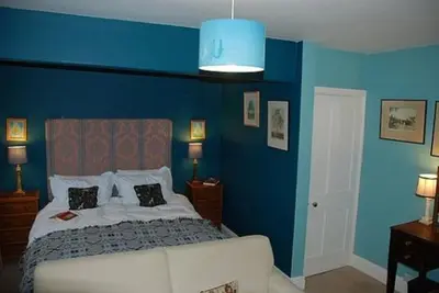 a blue bedroom with a bed and a blue wall at Lower Buckton Country House in Leintwardine