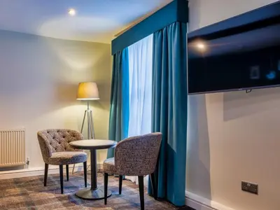 a room with two chairs and a table and a tv at The Feathers Hotel in Ludlow
