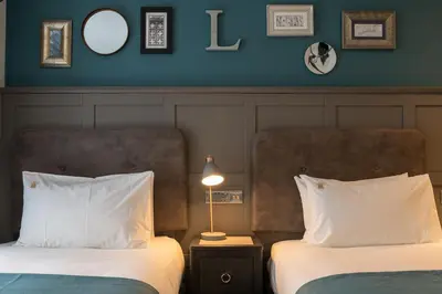 a hotel room with two beds and a lamp at The Feathers Hotel in Ludlow