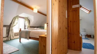 a bedroom with a bed and a bathroom with a window at Maes Glas in Mallwyd