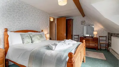 a bedroom with a bed with white sheets and a desk at Maes Glas in Mallwyd