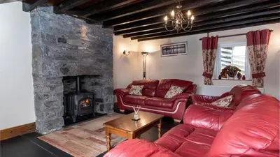 a living room with red leather couches and a stone fireplace at Maes Glas in Mallwyd