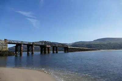 a bridge over the water next to a beach at Bae Abermaw Hotel in Barmouth