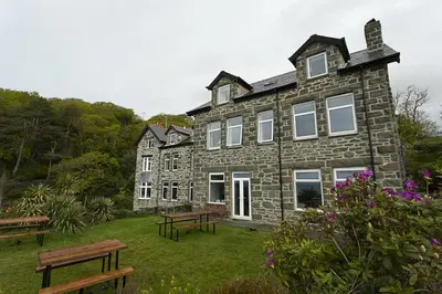 a large stone building with benches in front of it at Bae Abermaw Hotel in Barmouth