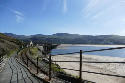 a beach with a fence next to a body of water at Bae Abermaw Hotel in Barmouth