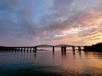 a bridge over the water with a sunset in the background at Bae Abermaw Hotel in Barmouth