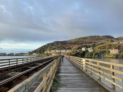 a person walking on a bridge over a body of water at Bae Abermaw Hotel in Barmouth