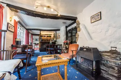 a living room with a fireplace and a table at Gwesty Minffordd Hotel in Tal-y-llyn