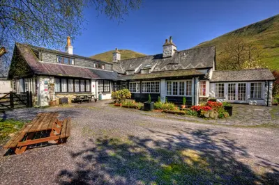 an exterior view of a house with a hill in the background at Gwesty Minffordd Hotel in Tal-y-llyn