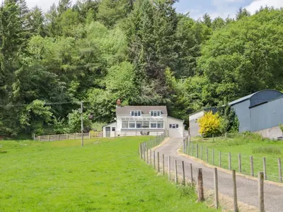 a farm house with a fence and a field at Caesamson in Caersws