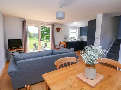 a living room with a blue couch and a wooden table at Owl Cottage in Llandrindod Wells