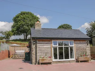 a small log cabin with a window and benches at The Boundary Annex in Bishops Castle