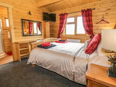 a bedroom with a bed in a wooden cabin at Manor Farm Lodges - Red Kite Lodge in Newtown