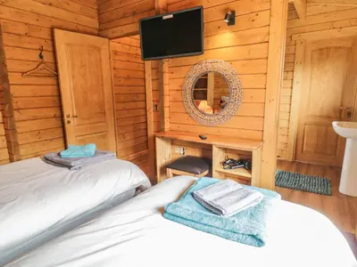 a bedroom with two beds in a wooden cabin at Manor Farm Lodges - Red Kite Lodge in Newtown