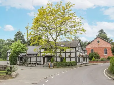 an old black and white building on the side of a road at Manor Farm Lodges - Red Kite Lodge in Newtown