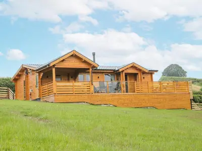 a log cabin with a large deck in a field at Manor Farm Lodges - Dragon Lodge in Newtown