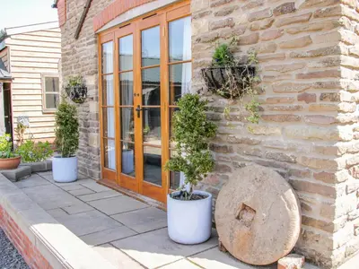 a stone building with three potted plants on a patio at High Grove in Ludlow