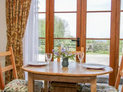 a table with two glasses and a vase of flowers on it at High Grove in Ludlow