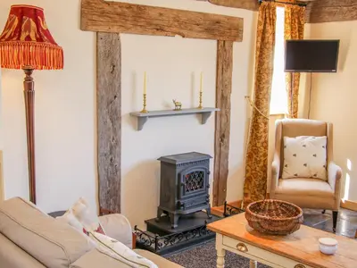 a living room with a wood stove and a chair at High Grove in Ludlow