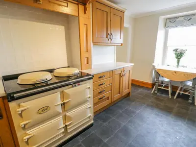 a kitchen with wooden cabinets and a stove top oven at Llety Perygl in Harlech