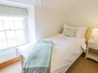 a white bed in a room with a window at Llety Perygl in Harlech