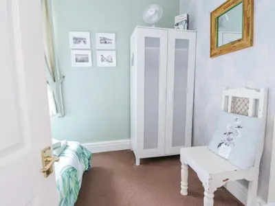 a room with a white cabinet and a chair at Minydon in Fairbourne