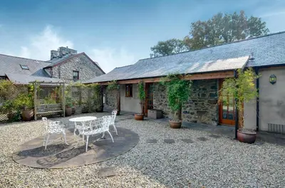 a patio with two chairs and a table in front of a building at 2 Bed in Tywyn oc-wah595 in Llanegryn