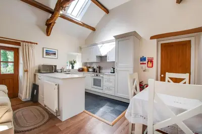a kitchen with white cabinets and a table at 2 Bed in Tywyn oc-wah595 in Llanegryn