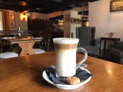 a cup of coffee on a table with a cookie at The Griffin Llyswen in Brecon