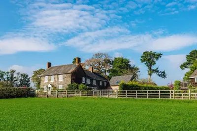 an old house in a field with a fence at Mid-Wales Farmhouse, swimming pool, tranquil countryside views, sleeps 14 in Meifod
