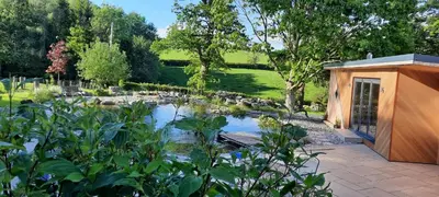 a small building with a pond in a garden at Mid-Wales Farmhouse, swimming pool, tranquil countryside views, sleeps 14 in Meifod