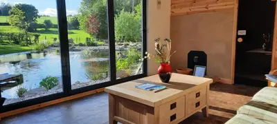 a living room with a large window with a view of a lake at Mid-Wales Farmhouse, swimming pool, tranquil countryside views, sleeps 14 in Meifod