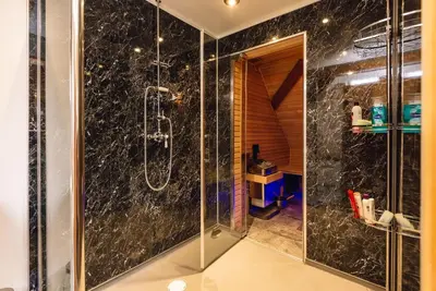 a bathroom with a shower with black marble at Mid-Wales Farmhouse, swimming pool, tranquil countryside views, sleeps 14 in Meifod