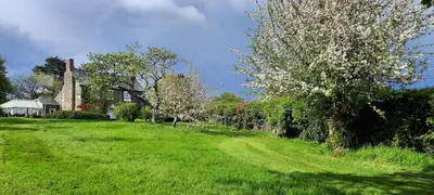 a field of green grass with a house and trees at Mid-Wales Farmhouse, swimming pool, tranquil countryside views, sleeps 14 in Meifod